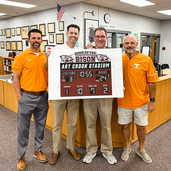 Principal Art Crook with leadership holding a scoreboard sign